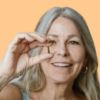 Older woman holding Herbaly's Glucose Blood Sugar Complete Capsule between her fingers